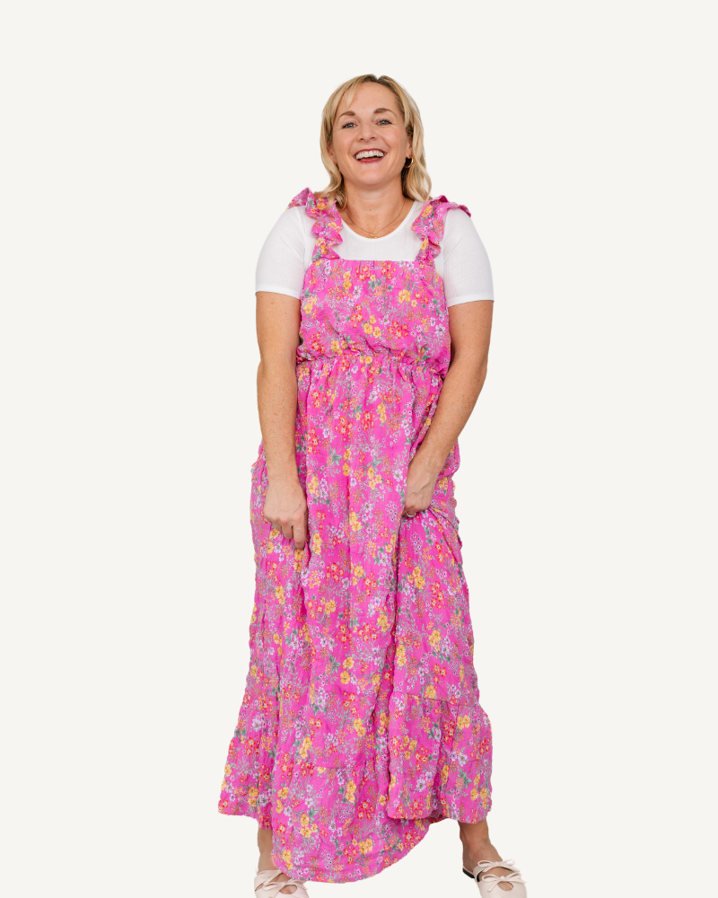 A woman in a floral ruffle-sleeved maxi dress is smiling.