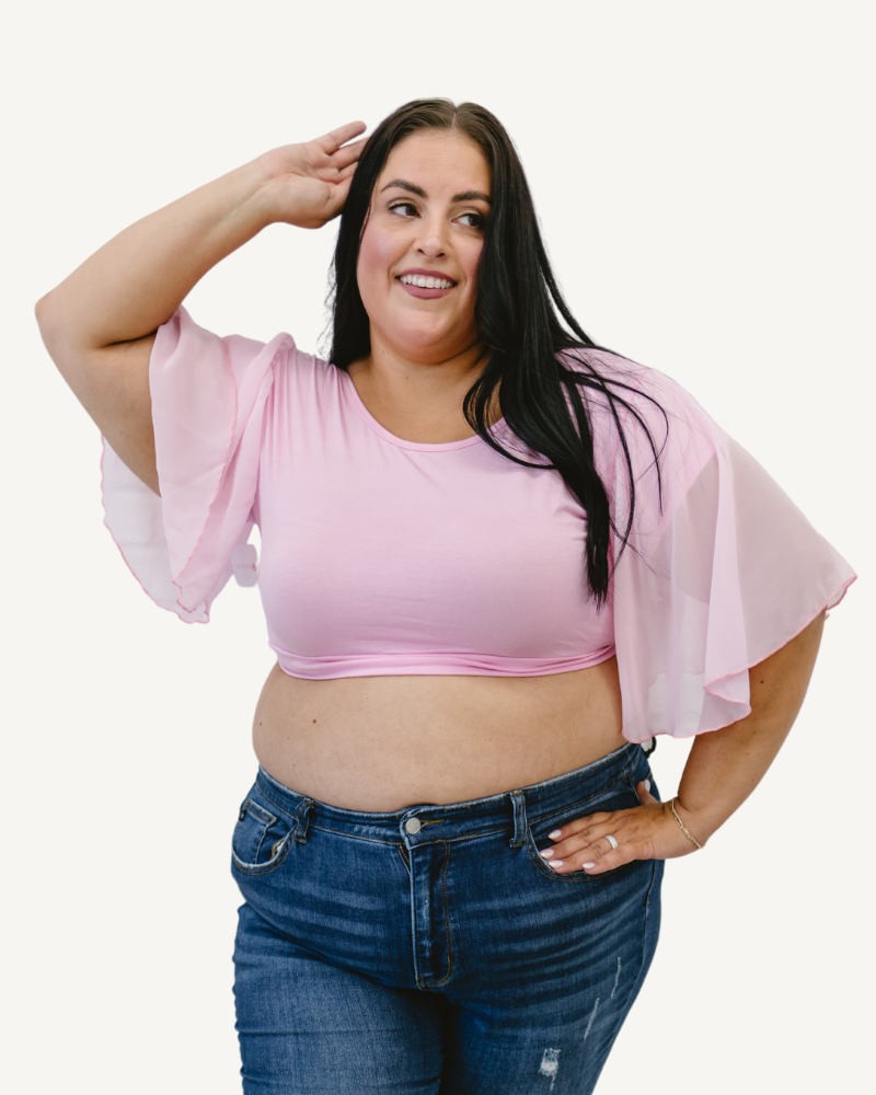 A plus size woman in a pink top and jeans, wearing a Waterfall Sleeved Halftee.