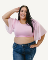 A plus size woman in a pink top and jeans, wearing a Waterfall Sleeved Halftee.