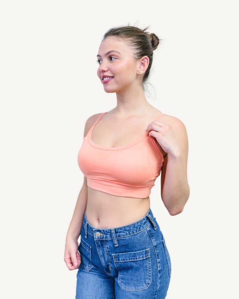 A woman wearing a pink bra top and jeans.