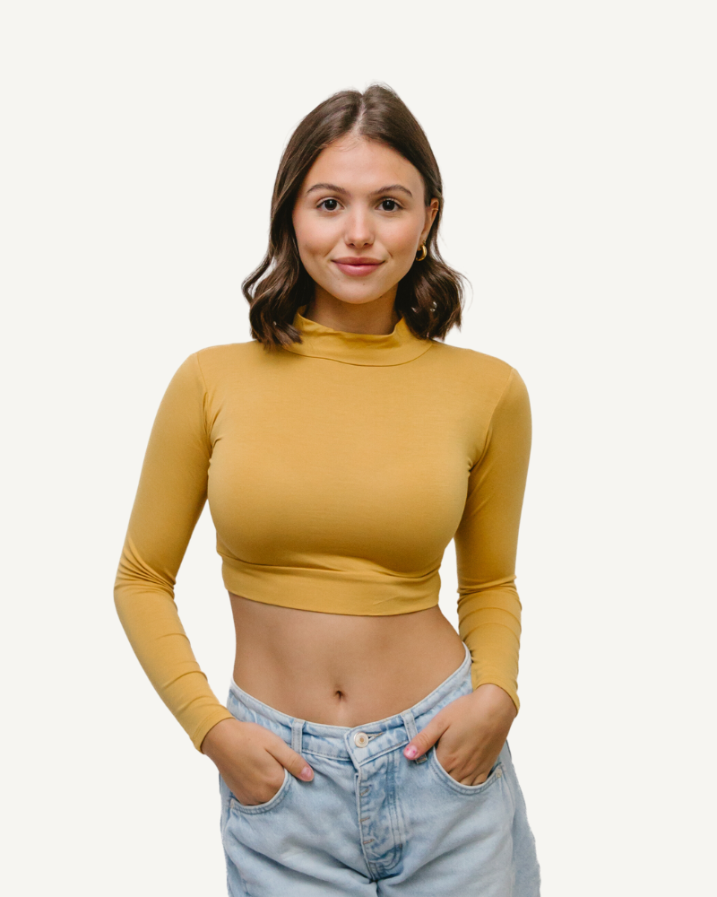A woman wearing a yellow crop top and jeans, with a mock long sleeve yellow design.