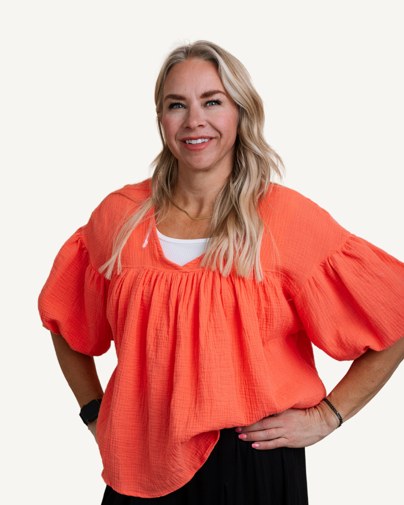 A woman wearing an orange gauze babydoll top.