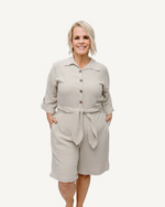 A Gray  linen romper with long sleeves and a tie waist. Perfect for a casual summer look.