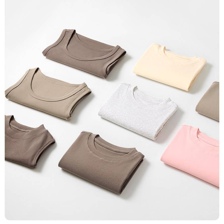 Folded t-shirts in beige, cream, gray, and pink are neatly arranged in rows on a white surface, conveying a sense of order and simplicity.
