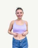 A woman wearing a taupe bra top and jeans.