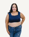 A curvy woman in a navy crop top and jeans, wearing a Peekaboo Short Sleeve Halftee with lace inset.