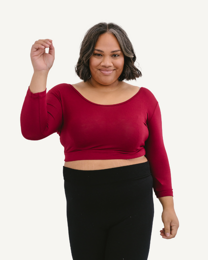 A plus size woman wearing a red crop top and jeans. (Discontinued 3/4 Colors)