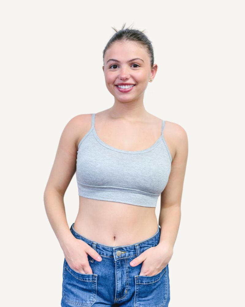 A woman wearing a gray bra top and jeans.