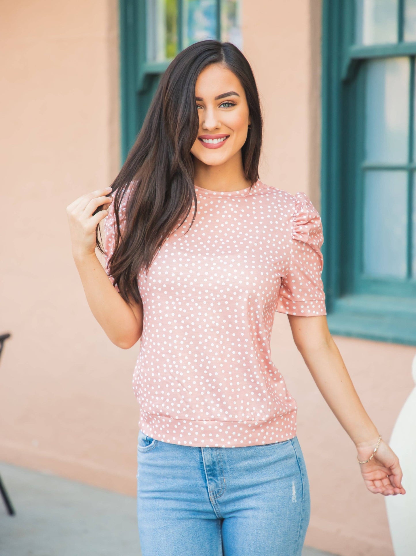 A woman sporting a red floral blouse and jeans exemplifies a stylish and easygoing fashion sense.