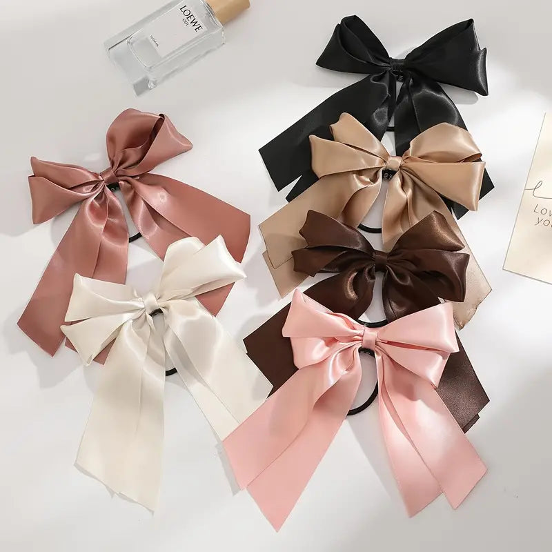 A collection of four colorful bow hair ties, each featuring a unique hue, perfect for adding flair to any hairstyle.