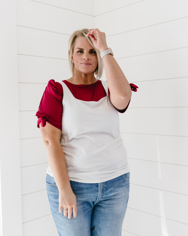 woman in a red  top and jeans, wearing a Puff Sleeve Halftee with Tie Detail.