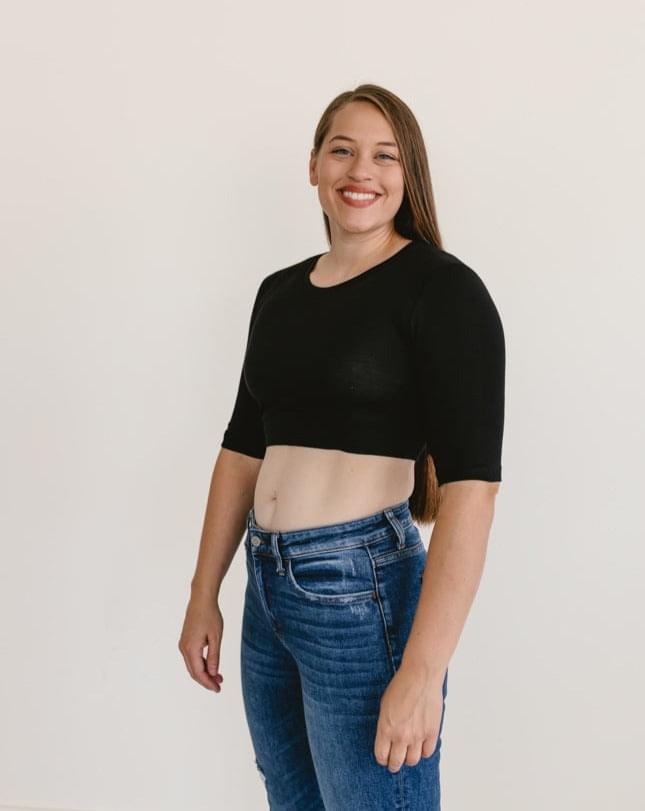 A woman wearing a black  crew neck elbow sleeve top and jeans.