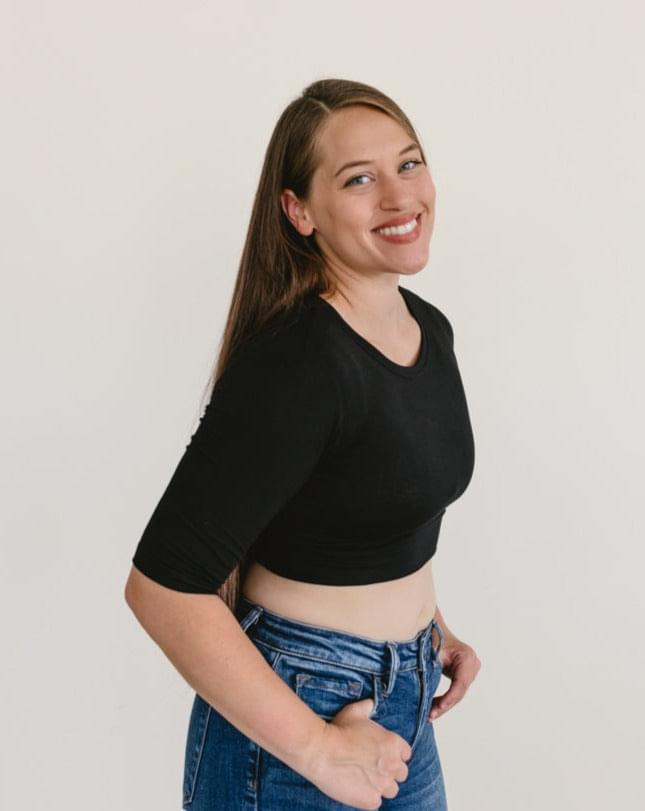 A woman wearing a black crew neck elbow sleeve top and jeans.