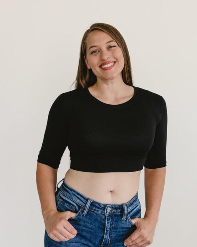 A woman wearing a black crew neck elbow sleeve top and jeans.