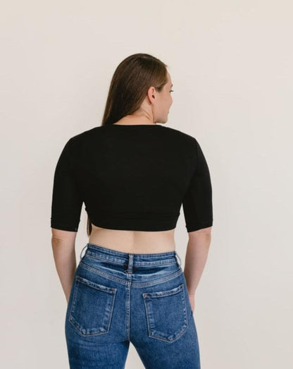 A woman wearing a black crew neck elbow sleeve top and jeans.