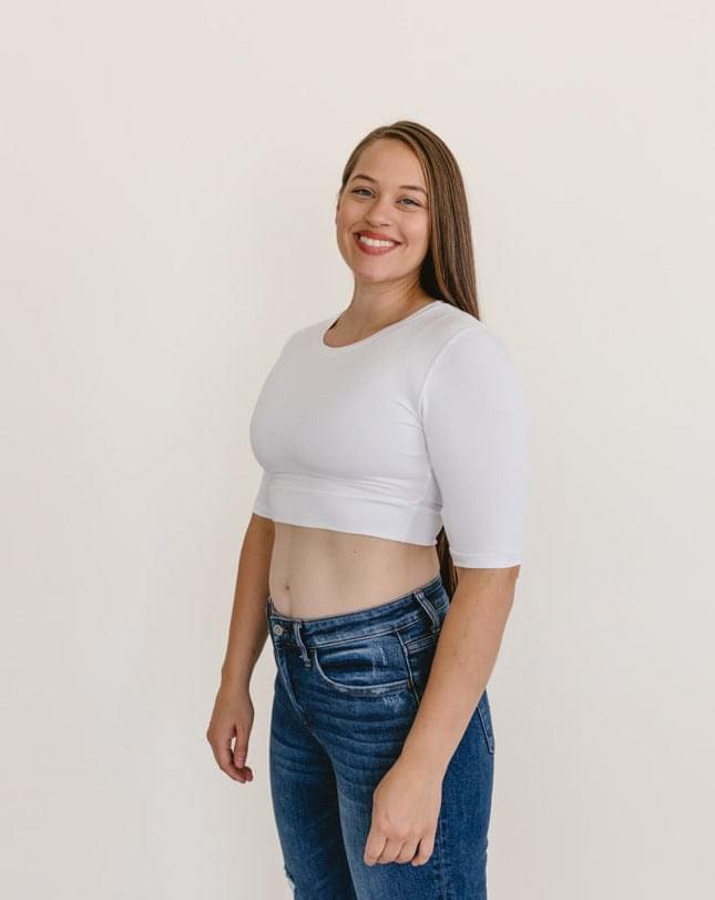 A woman wearing a white crew neck long sleeve top and jeans.