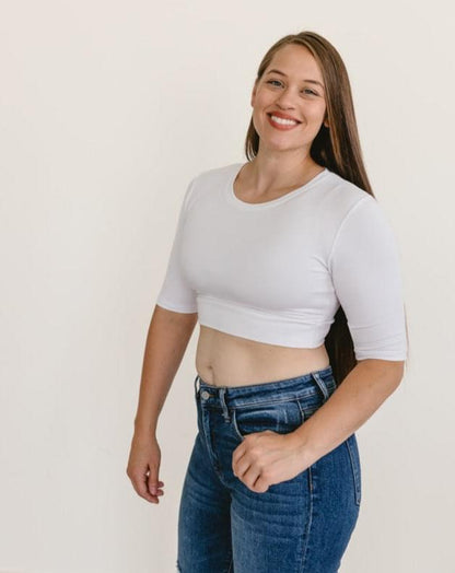 A woman wearing a white crew neck elbow sleeve top and jeans.