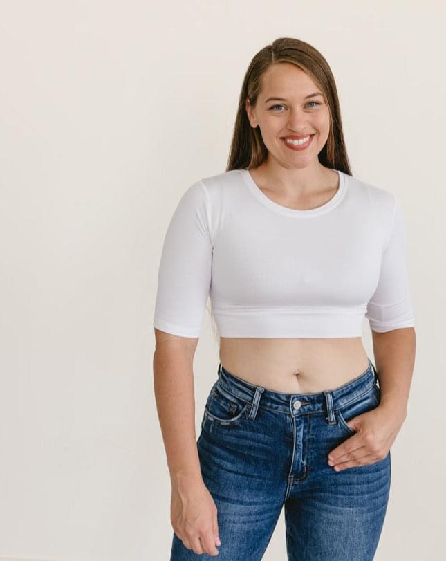 A woman wearing a white crew neck elbow sleeve top and jeans.