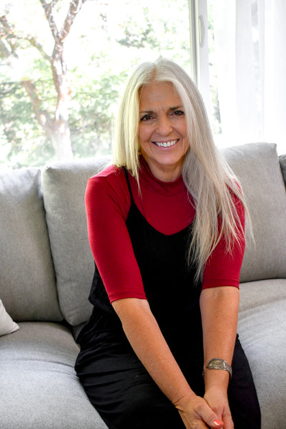 A woman with long white hair is seated gracefully on a couch, exuding a serene and contemplative presence.