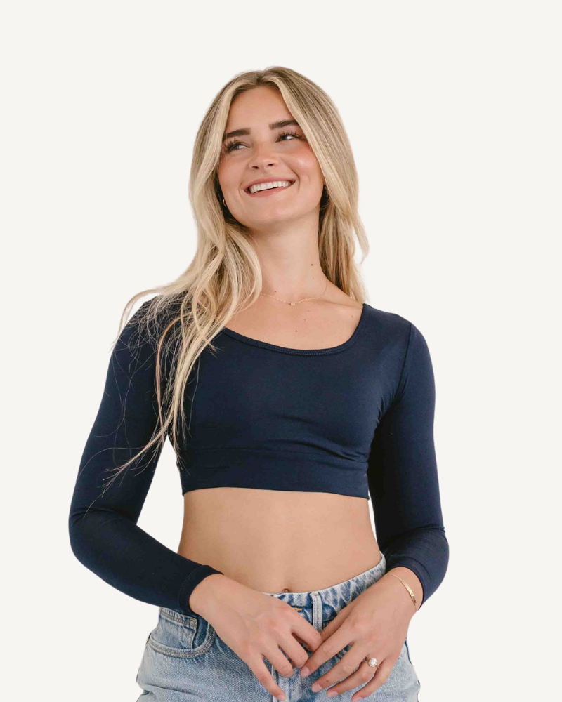 A woman in a navy  crop top and jeans, wearing a Classic Long Sleeve Halftee.