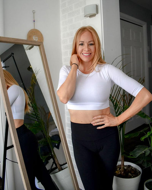 A woman wearing a white crew neck elbow sleeve top and jeans.