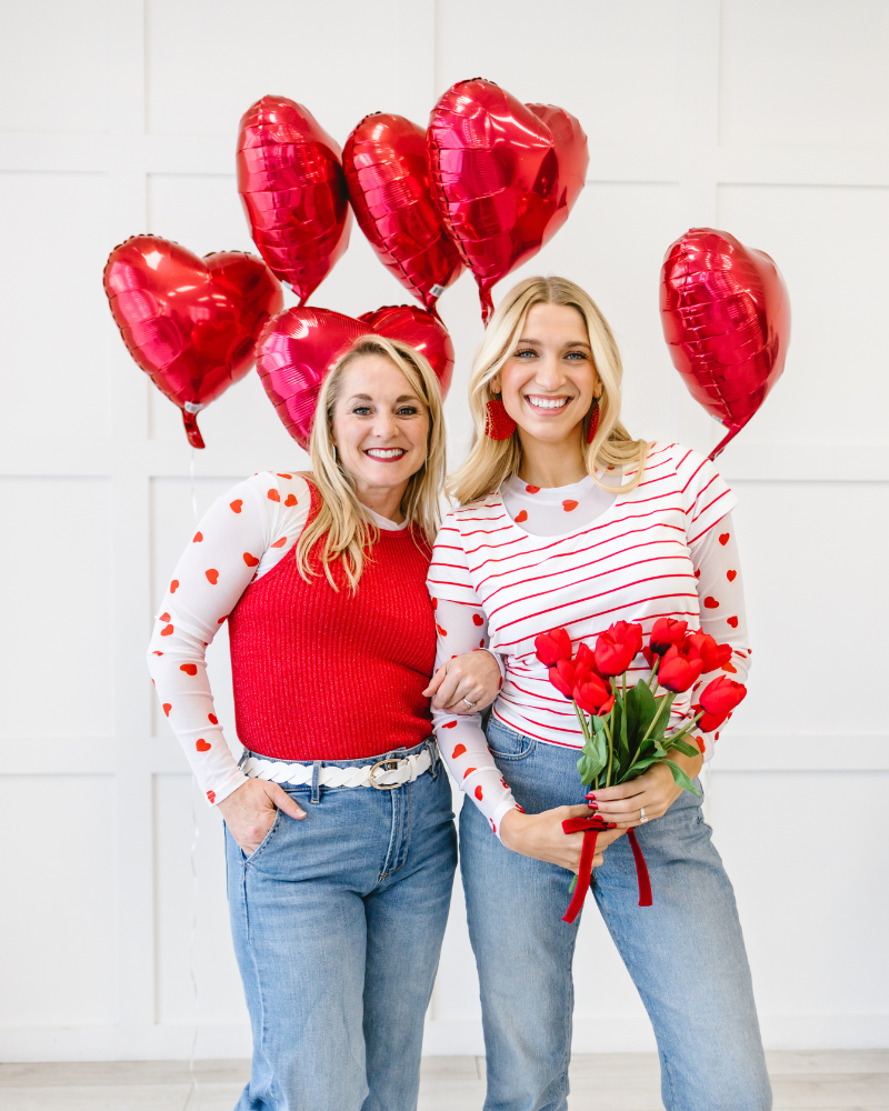 Two women happily hold red hearts and balloons, featuring the word "new" to promote HALFTEE Layering Fashions.