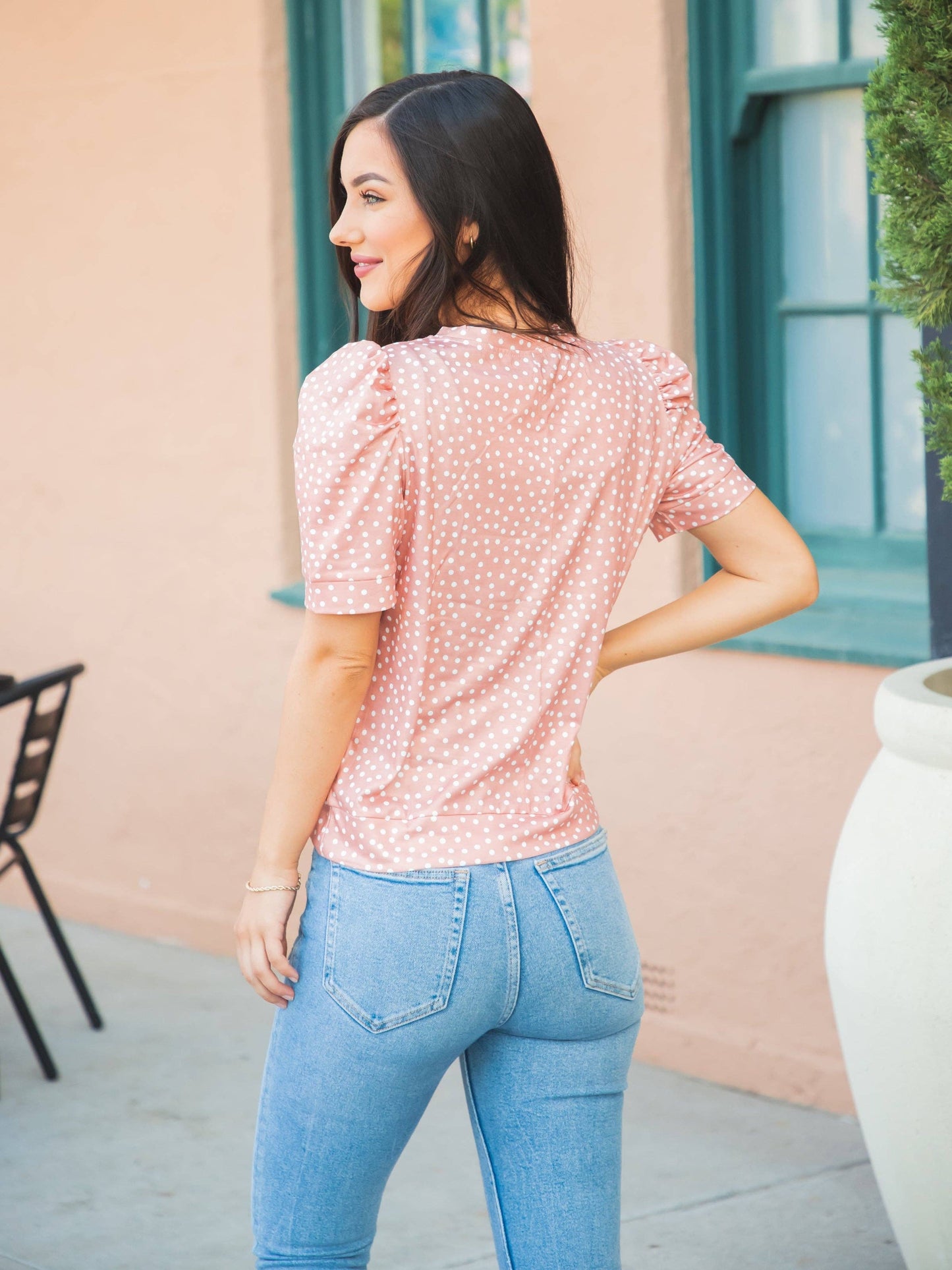 A woman in a red floral top and jeans radiates a laid-back yet fashionable vibe.