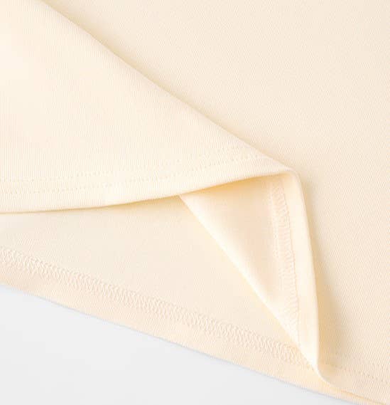 A close-up image of a cream-colored fabric with a corner neatly folded over. The fabric appears smooth and soft, conveying a sense of warmth and comfort.