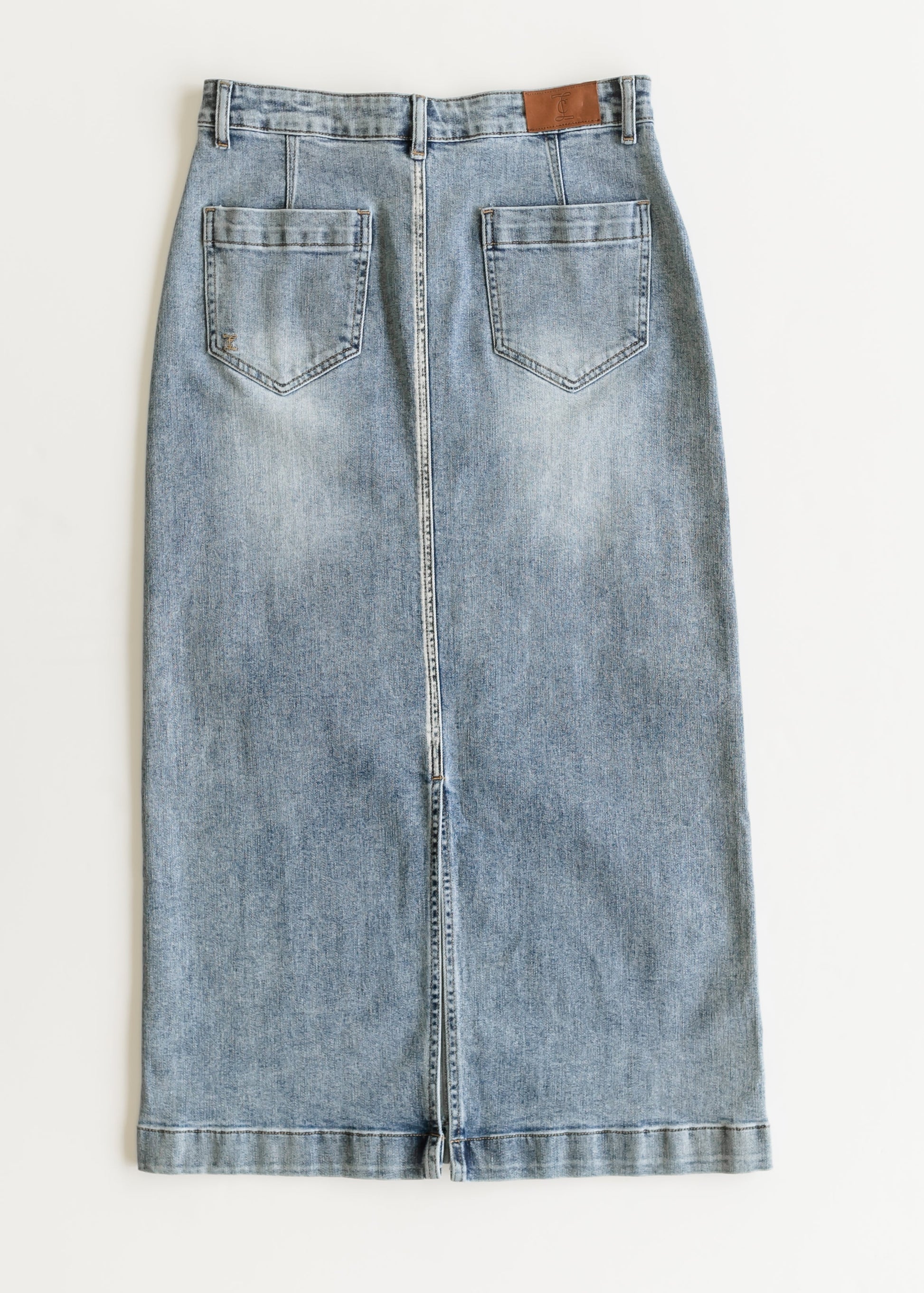 Long denim skirt with a straight cut, featuring two back pockets and a brown label near the waistband. Fabric is light blue with a faded wash effect.