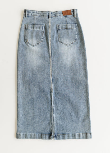 Long denim skirt with a straight cut, featuring two back pockets and a brown label near the waistband. Fabric is light blue with a faded wash effect.