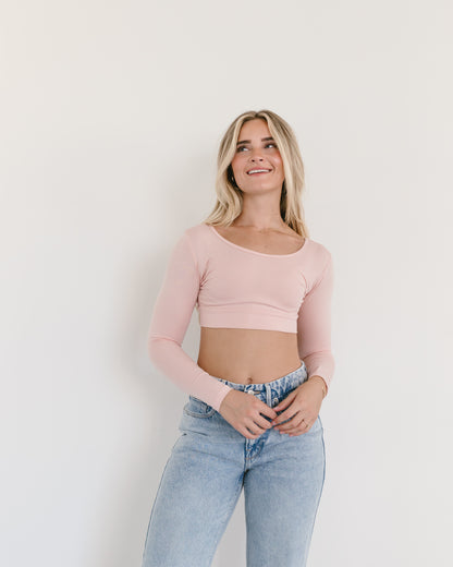 A woman in a nude crop top and jeans, wearing a Classic Long Sleeve Halftee.