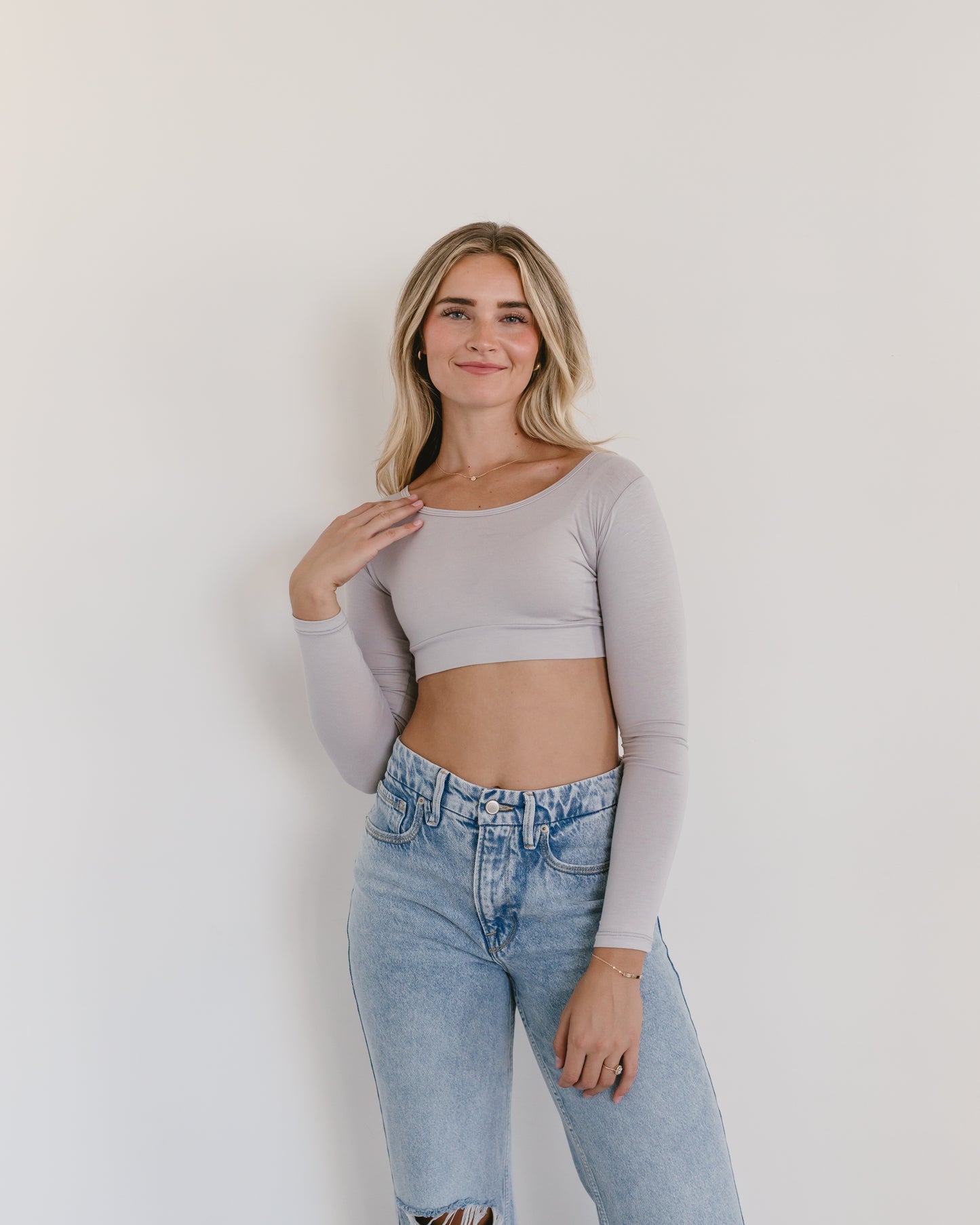 A woman in a gray crop top and jeans, wearing a Classic Long Sleeve Halftee.