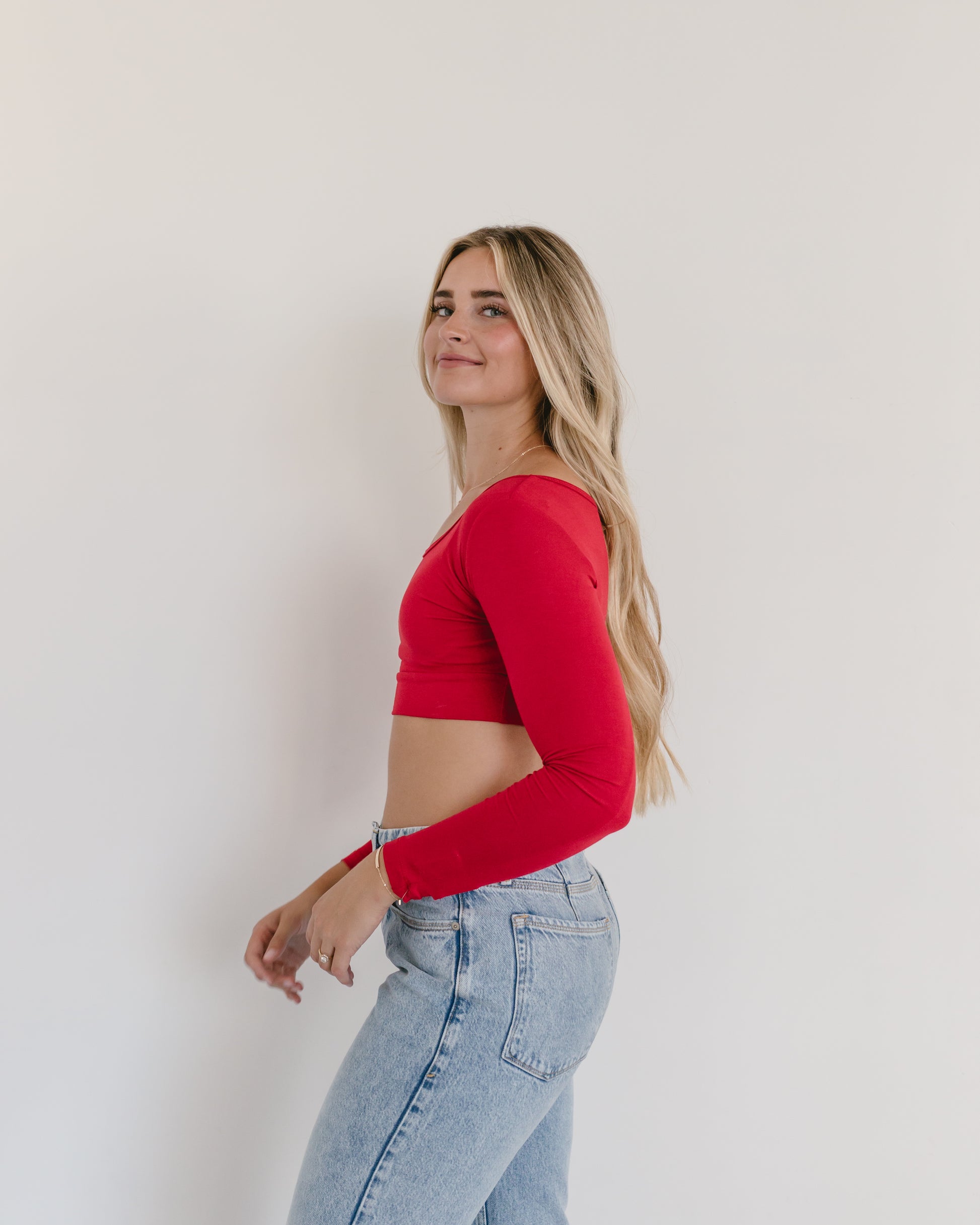 A woman in a red crop top and jeans, wearing a Classic Long Sleeve Halftee.