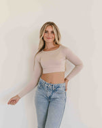 A fashionable woman in a crop top and jeans, exuding confidence and style in a casual setting.