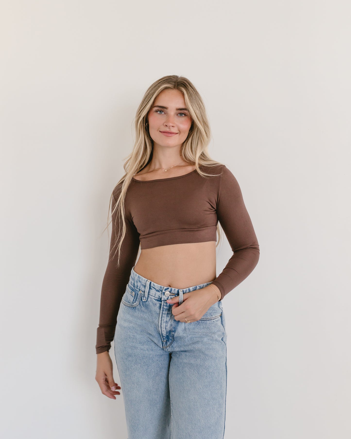 A woman in a brown crop top and jeans, wearing a Classic Long Sleeve Halftee.