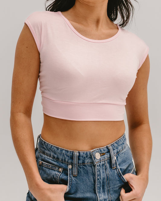 Woman wearing a pink Halftee crop top with short sleeves and blue denim jeans