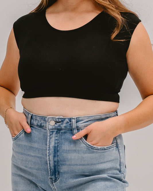 Woman wearing a black Halftee crop top with short sleeves and blue denim jeans