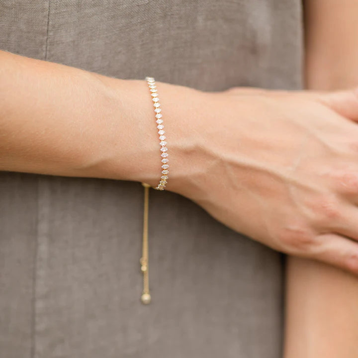 A woman in a green dress adorned with gold bracelets.