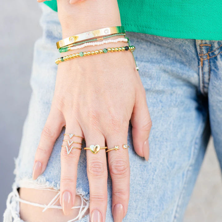 Adjustable layered ring sin woman hands wearing jeans and green  shirt