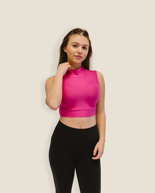 A woman in a pink crop top and black leggings. Discontinued Mock Sleeveless Colors.