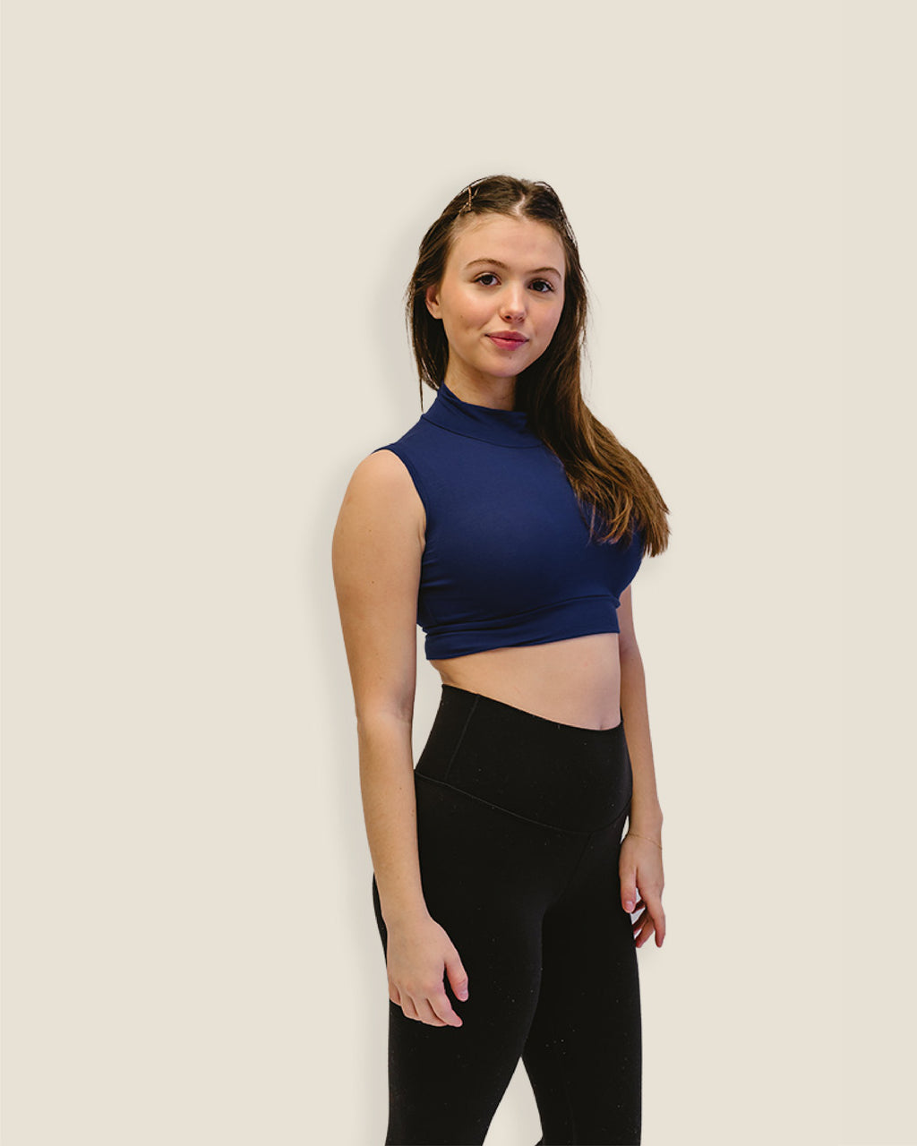 A woman in a navy crop top and black leggings. Discontinued Mock Sleeveless Colors.