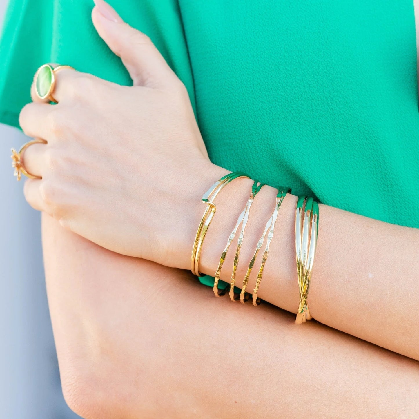 A woman in a green dress adorned with gold bracelets.