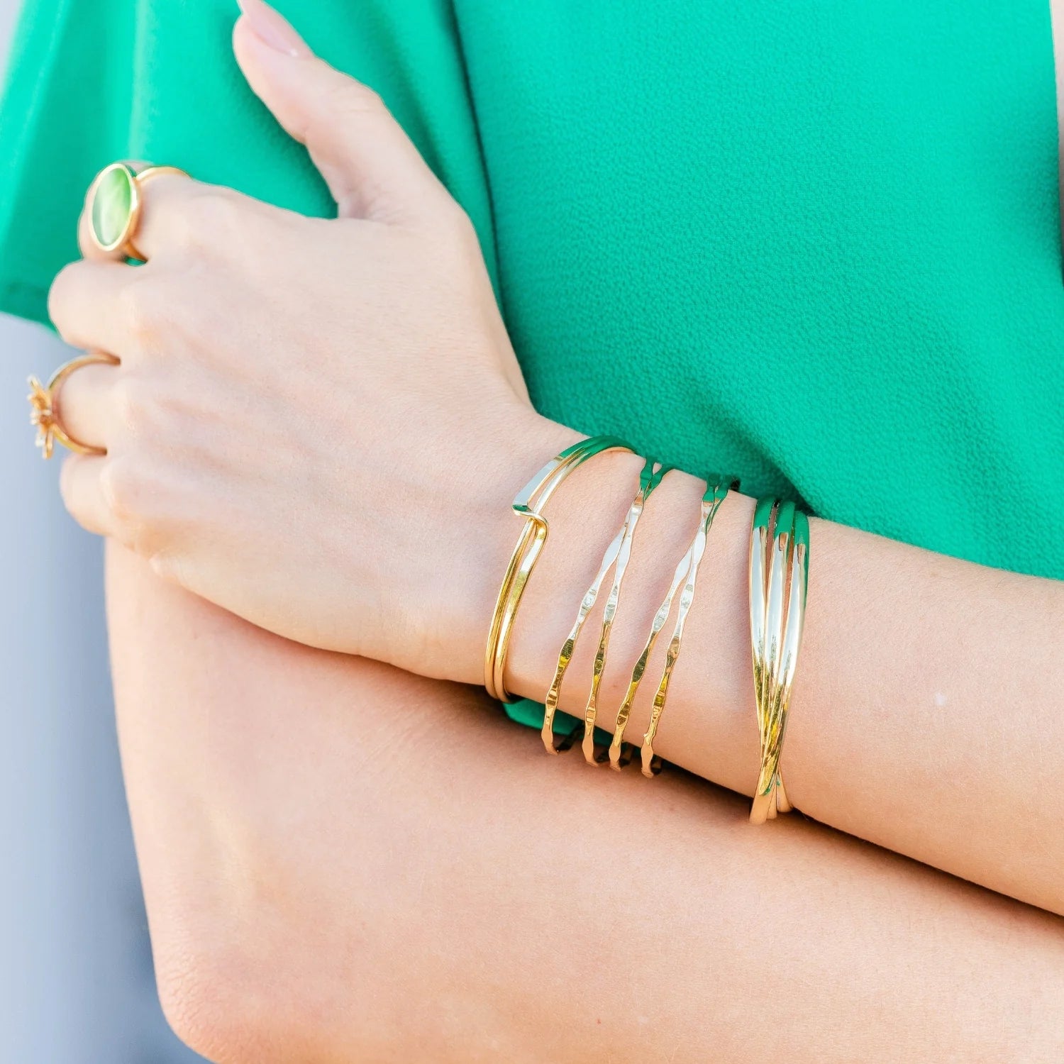 A woman in a green dress adorned with gold bracelets.