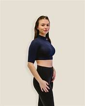 A woman wearing black leggings and a crop top stands confidently, showcasing a stylish and athletic look.