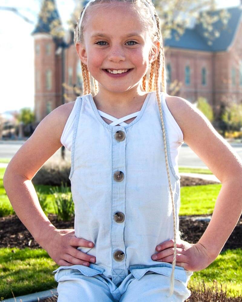 Young girl with braids sitting on bench, wearing GIRLEE Criss-Cross Tank.