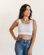 woman in a white crop top and jeans, wearing a Peekaboo Short Sleeve Halftee with lace inset.