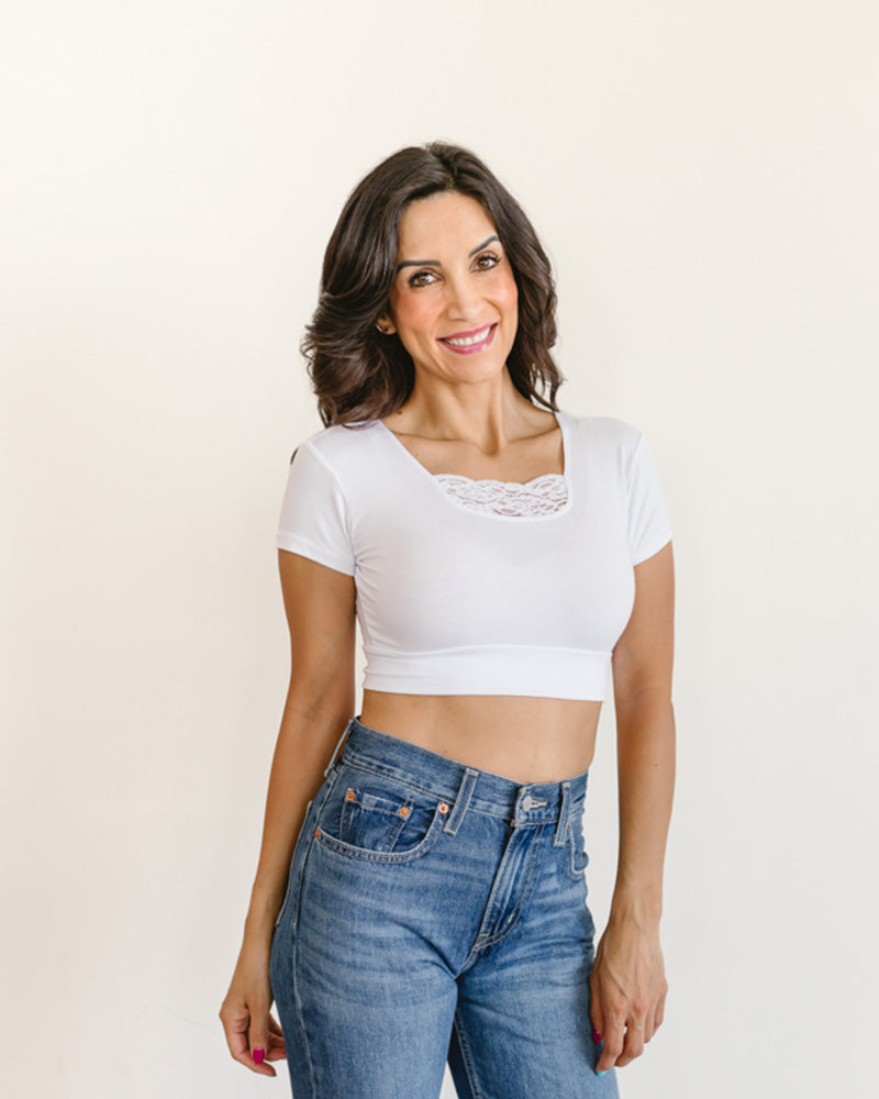 woman in a white crop top and jeans, wearing a Peekaboo Short Sleeve Halftee with lace inset.