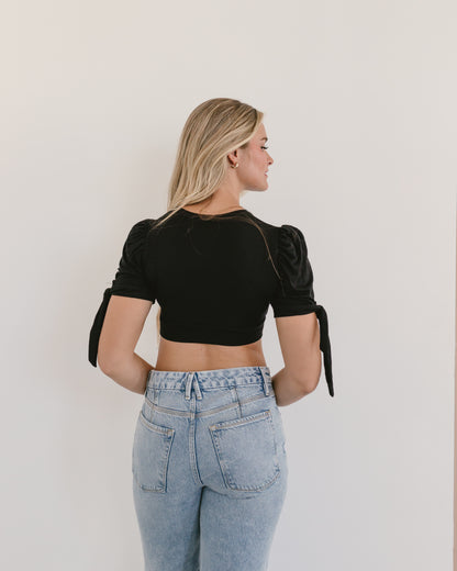 woman in a black top and jeans, wearing a Puff Sleeve Halftee with Tie Detail.