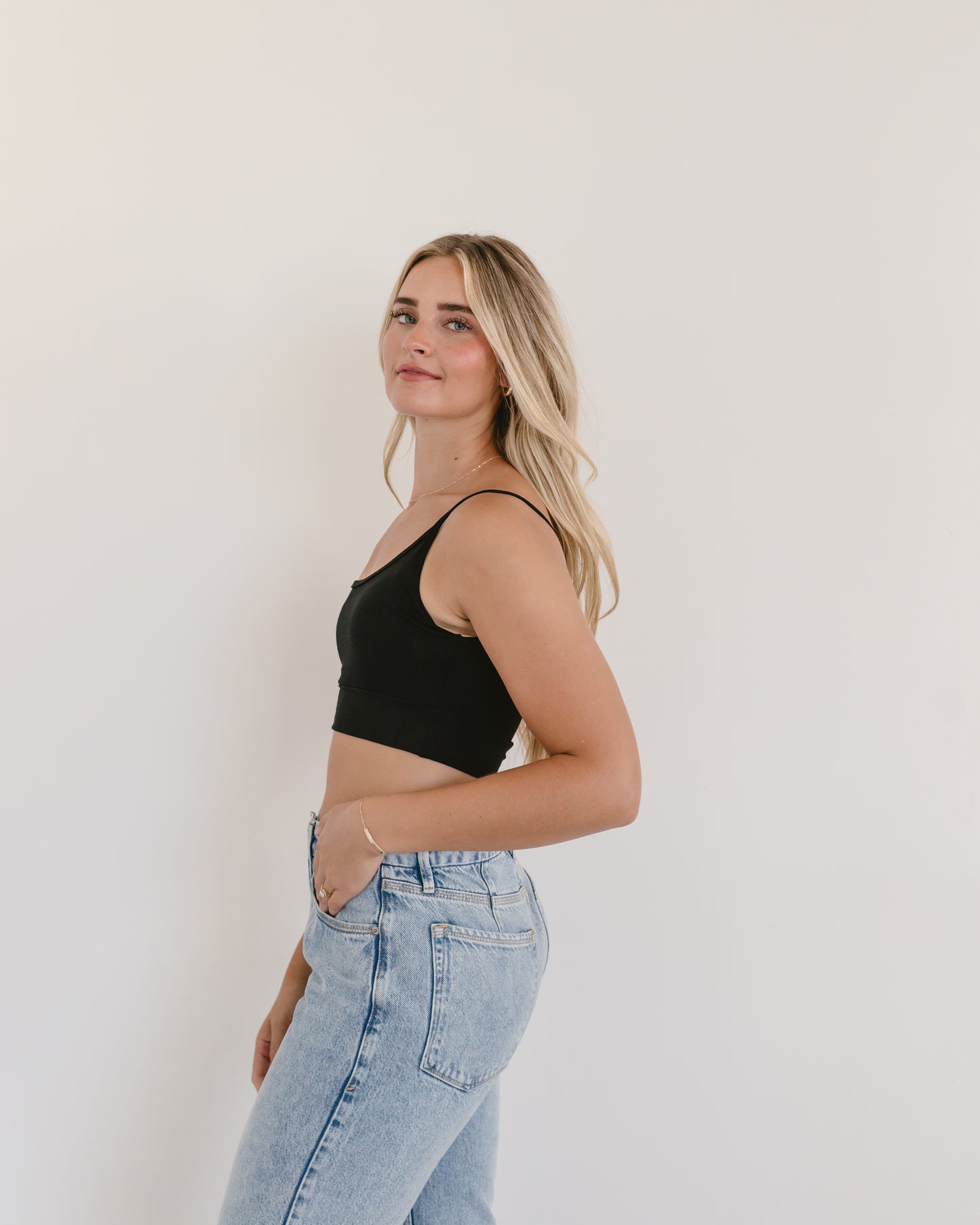 Woman in jeans and black crop top, wearing black Spaghetti Strap Halftee.