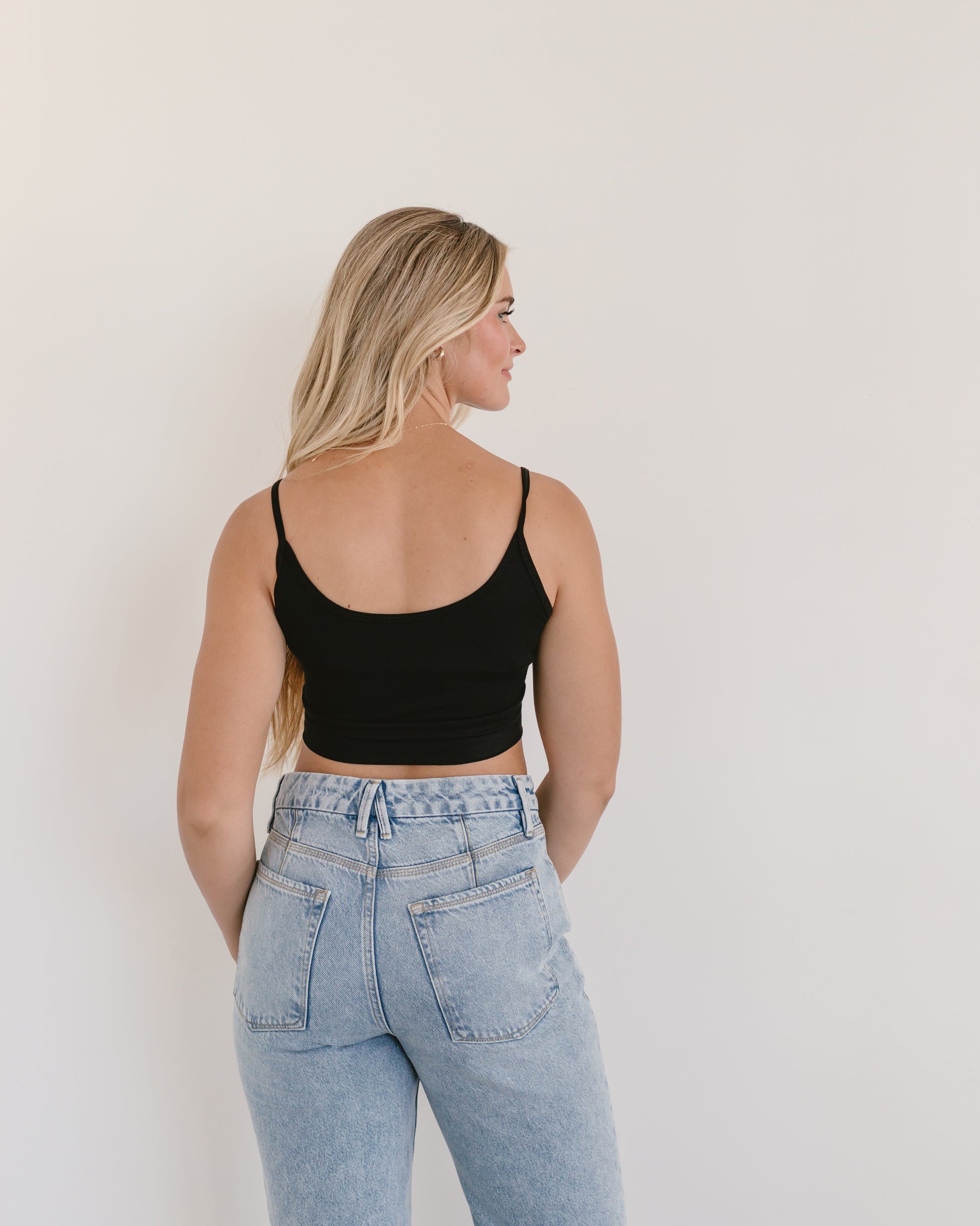 Woman in jeans and black crop top, wearing black Spaghetti Strap Halftee.